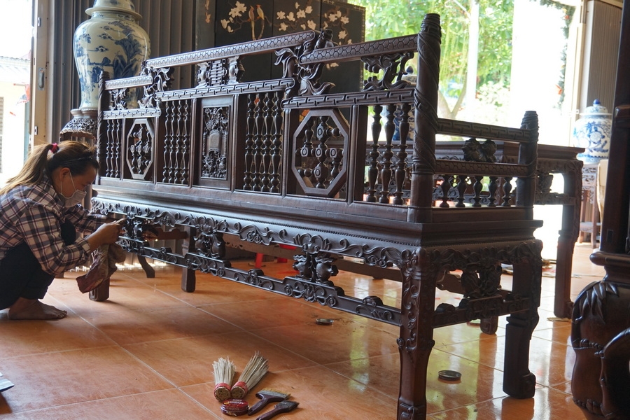 Người thợ đang lau xi sáp để lấy độ bóng cho tác phẩm trường kỷ Huế vân khúc